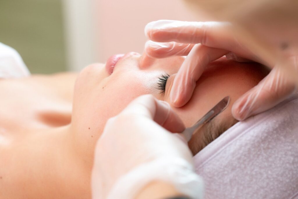 A person is getting their face shaped with scissors.